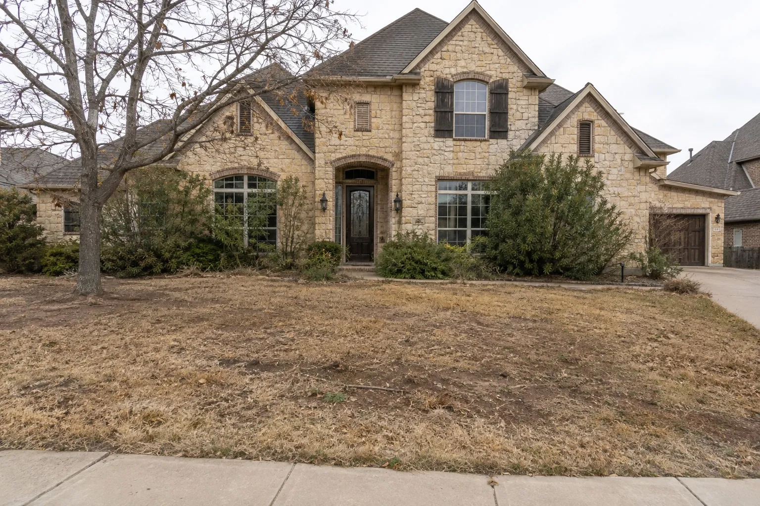 Front yard before the makeover with patchy grass and overgrown shrubs